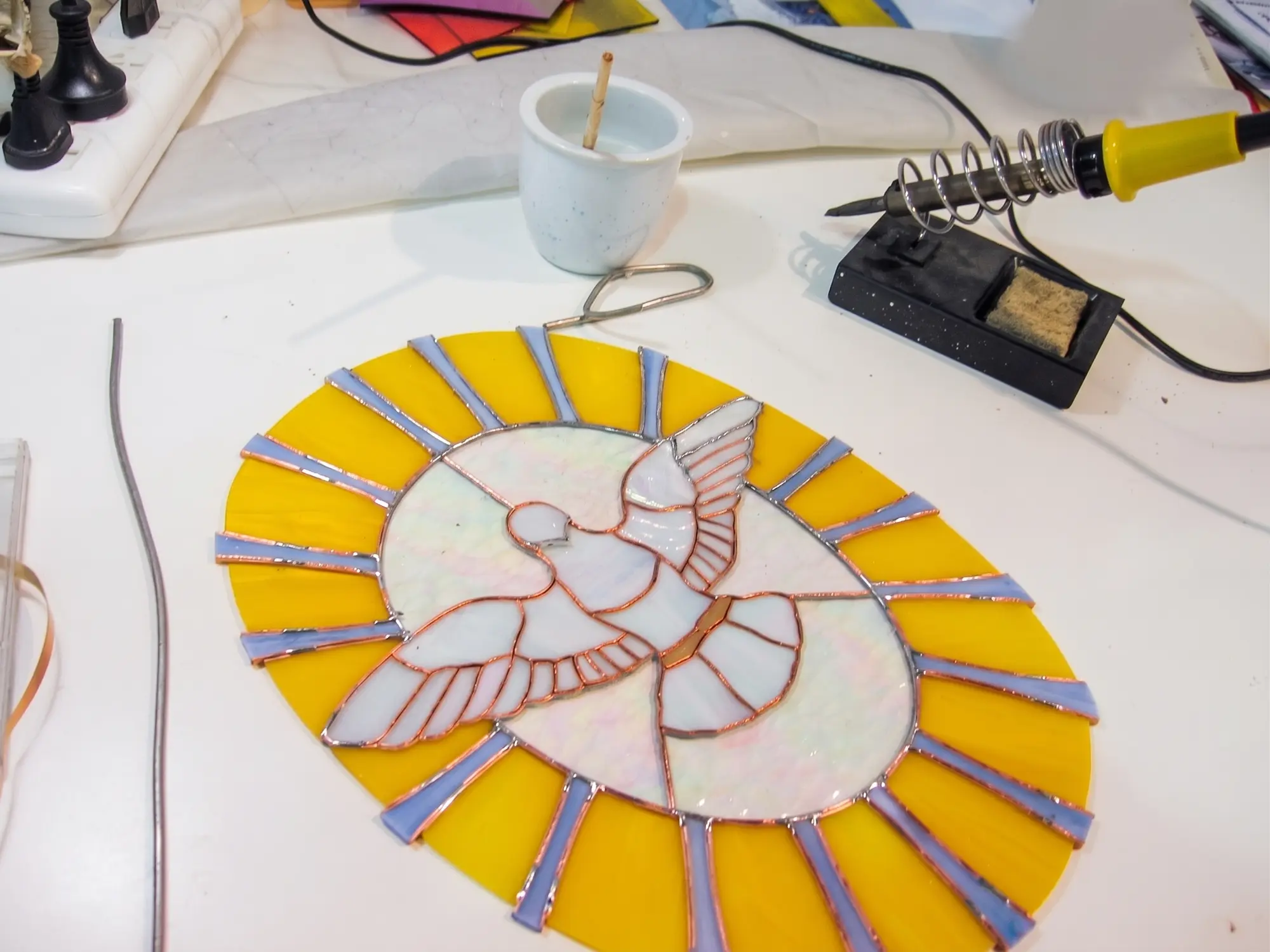 Vitral con paloma durante la soldadura en el taller.
