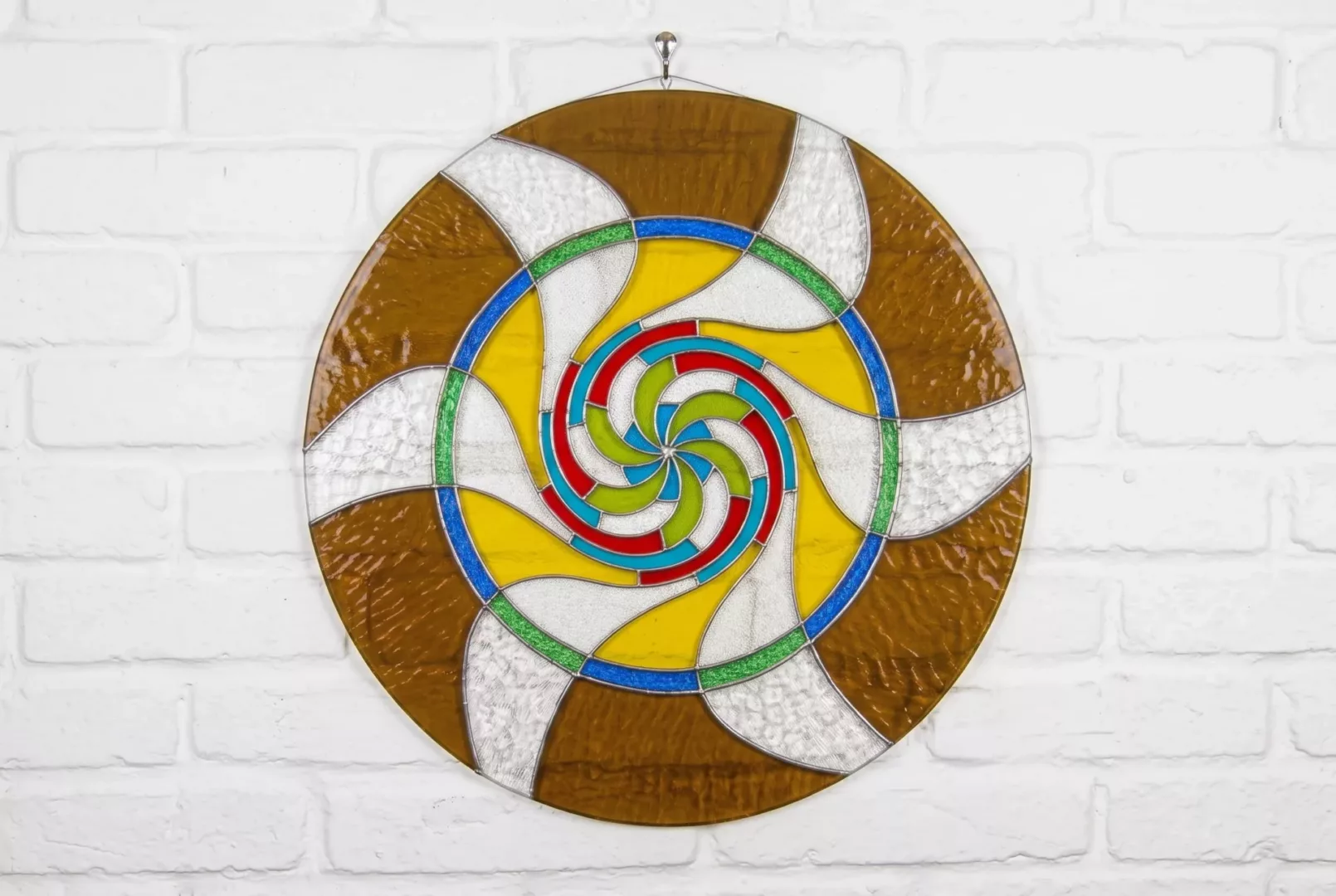 Mandala de vidrio multicolor con diseño espiral.
